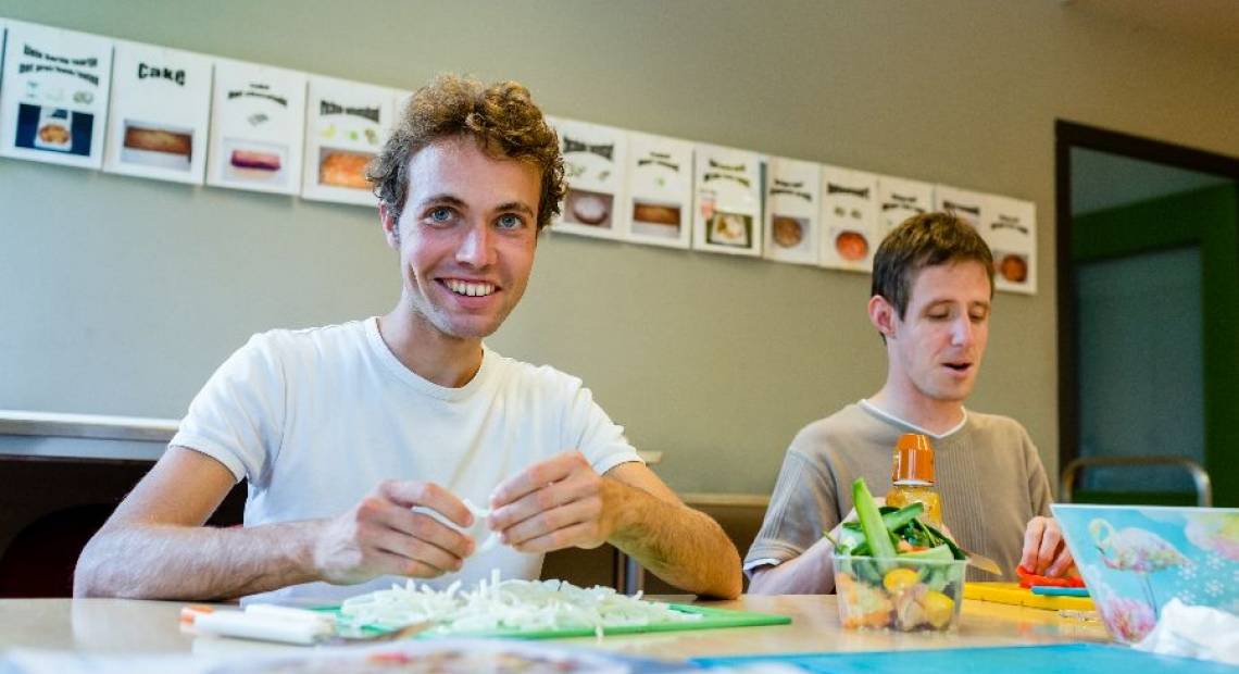 Twee jongemannen zijn eten aan het klaarmaken