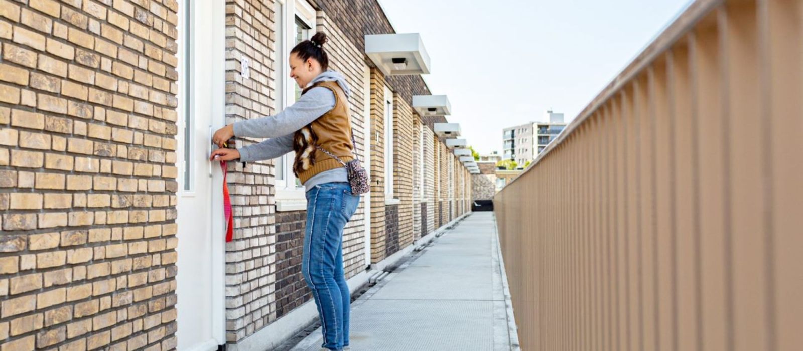 Jonge vrouw doet de voordeur open van haar appartement