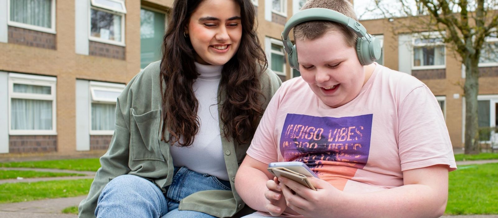 Een begeleider van OBC zit met een kind op een bankje