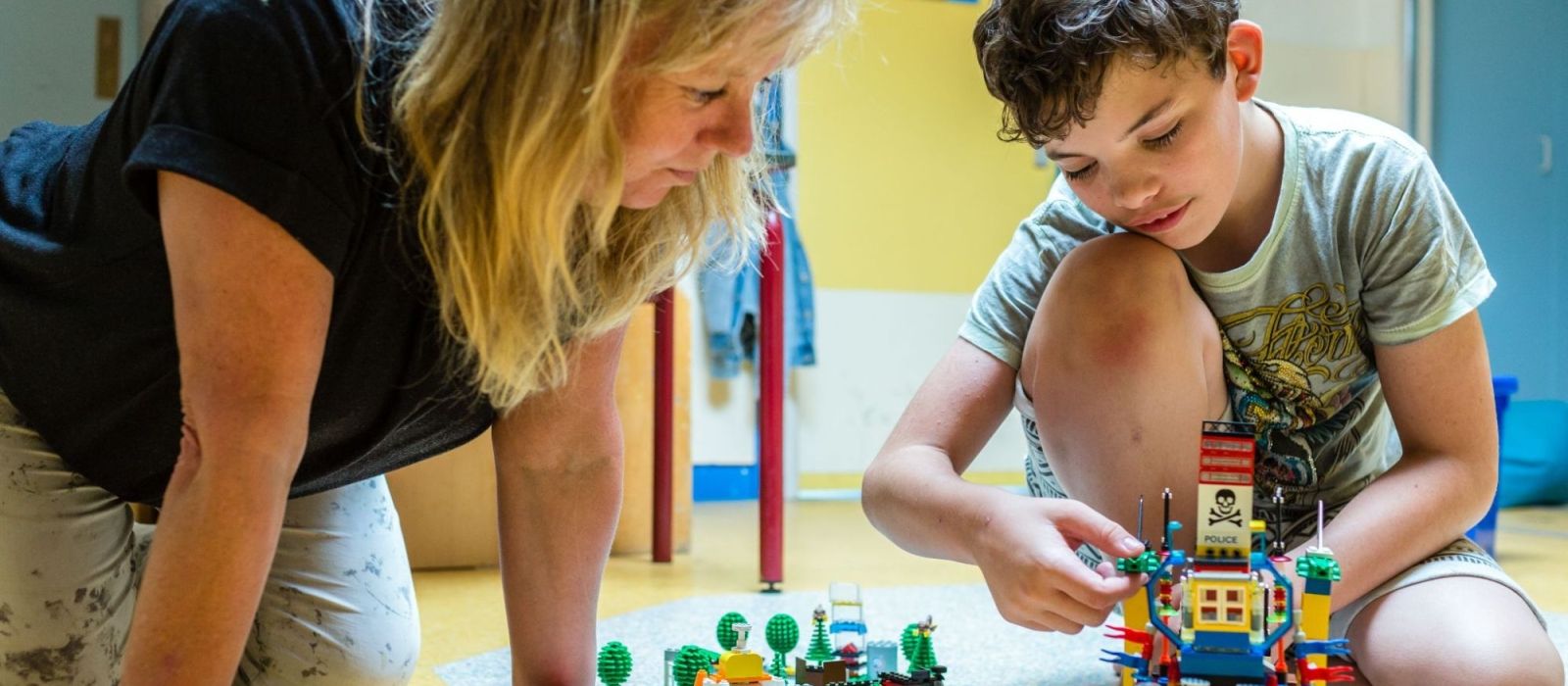 Begeleider speelt lego samen  met een jongen