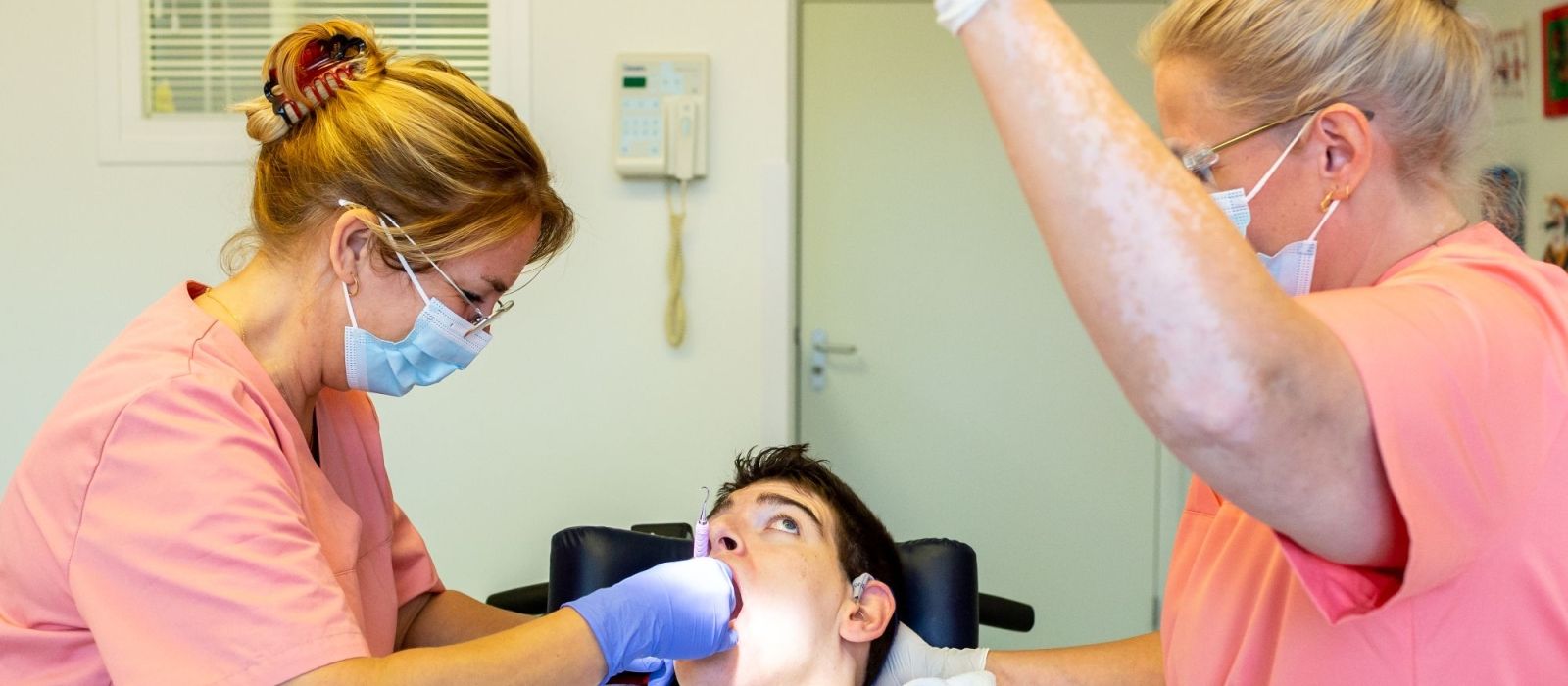 Tandarts en tandartsassistente bekijken tanden van een cliënt