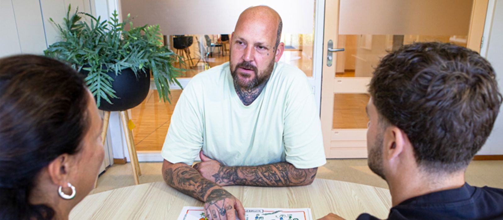 Beeld van de VGN we zien een begeleider in gesprek met cliënt en verwant.