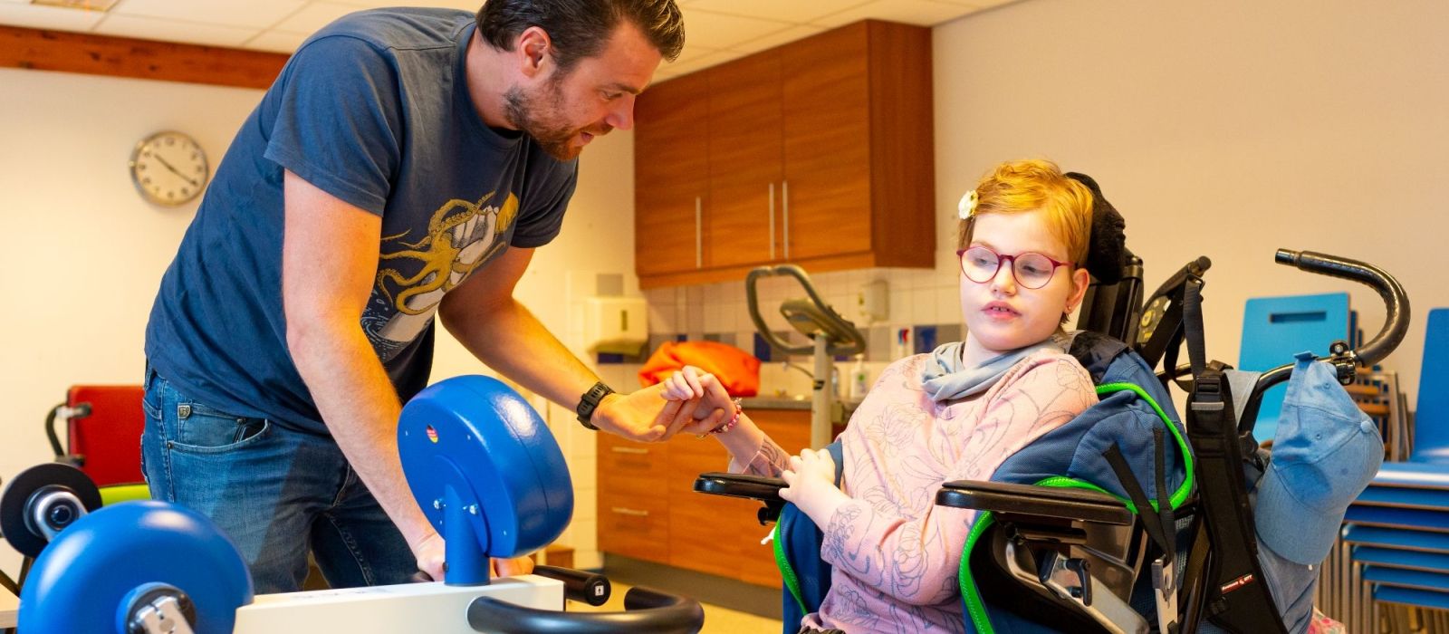 Begeleider helpt een cliënt in een rolstoel