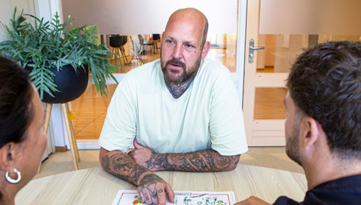 Beeld van de VGN we zien een begeleider in gesprek met cliënt en verwant.