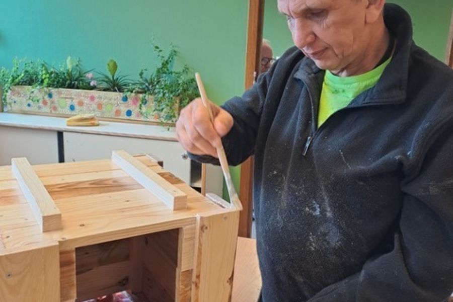 medewerker op dagbesteding de boei verft een egelkast